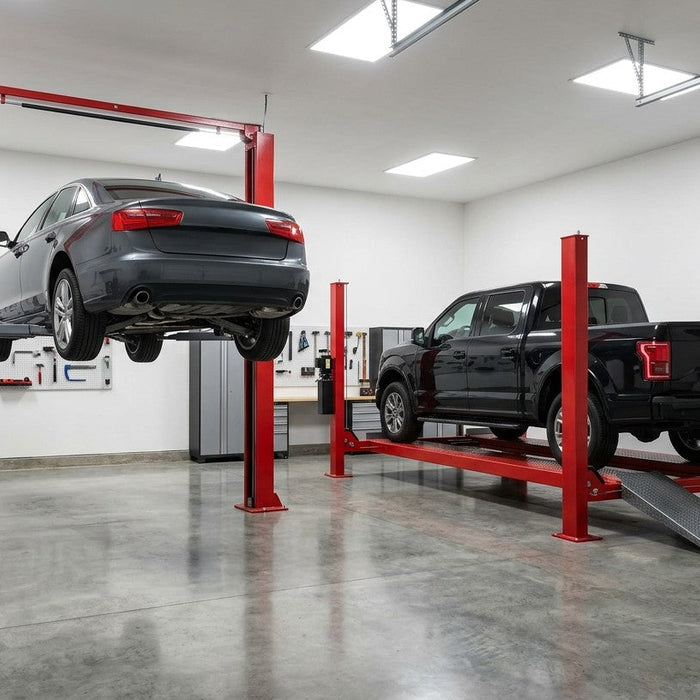 Sedan on a red two-post lift beside a pickup truck on a red four-post lift in a bright garage